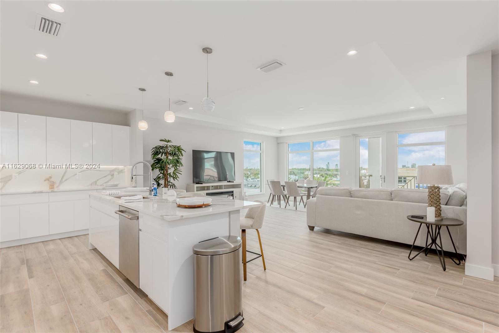 a large white kitchen with sink a stove a dining table and chairs