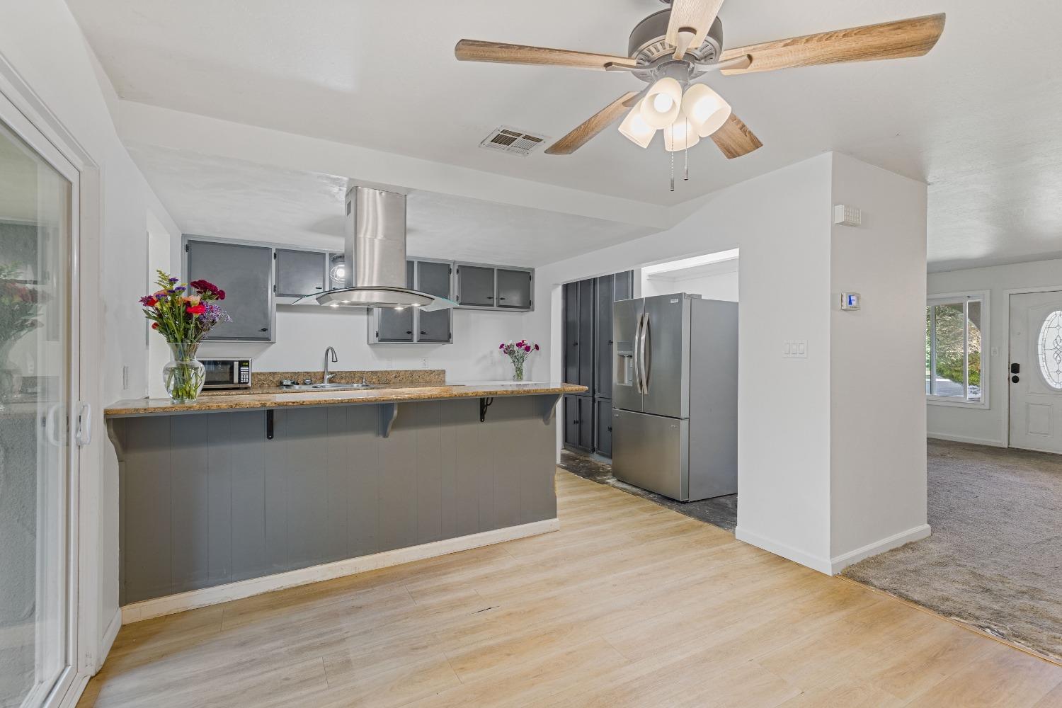 a room with kitchen island stainless steel appliances sink cabinets and window