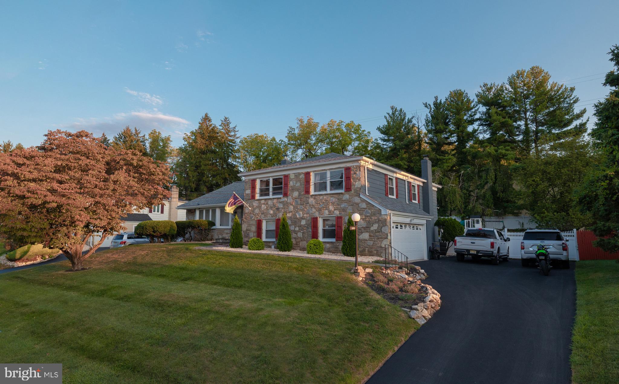 a front view of a house with a garden and trees