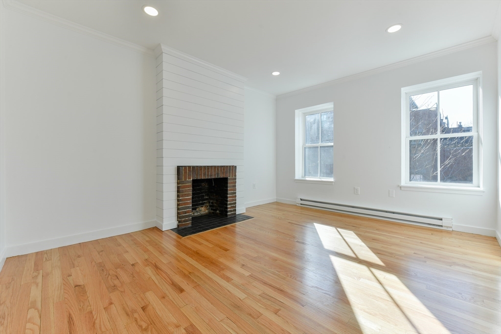 a view of empty room with a fireplace and wooden floor