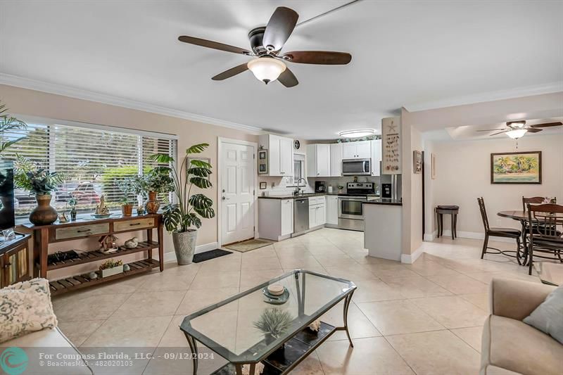 a living room with furniture kitchen view and a large window