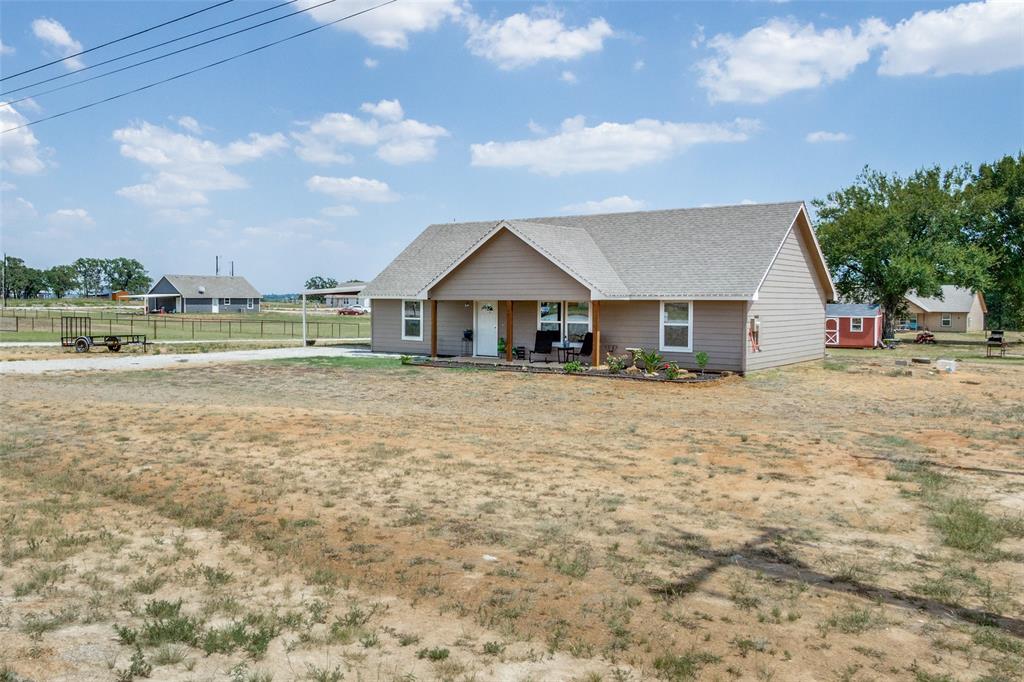 a view of a house with a yard and a large tree