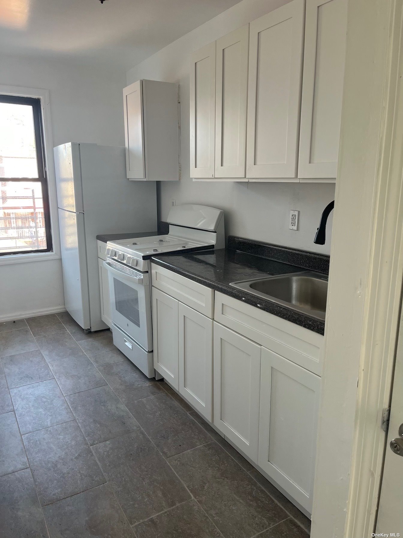 a kitchen with granite countertop white cabinets and white appliances