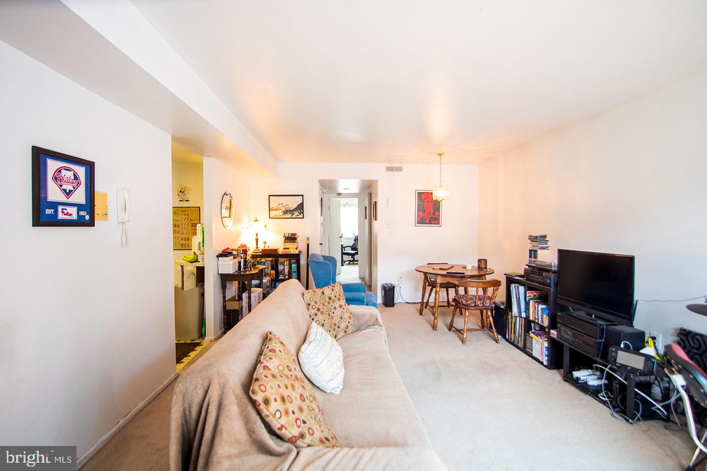 a living room with furniture a flat screen tv and a refrigerator