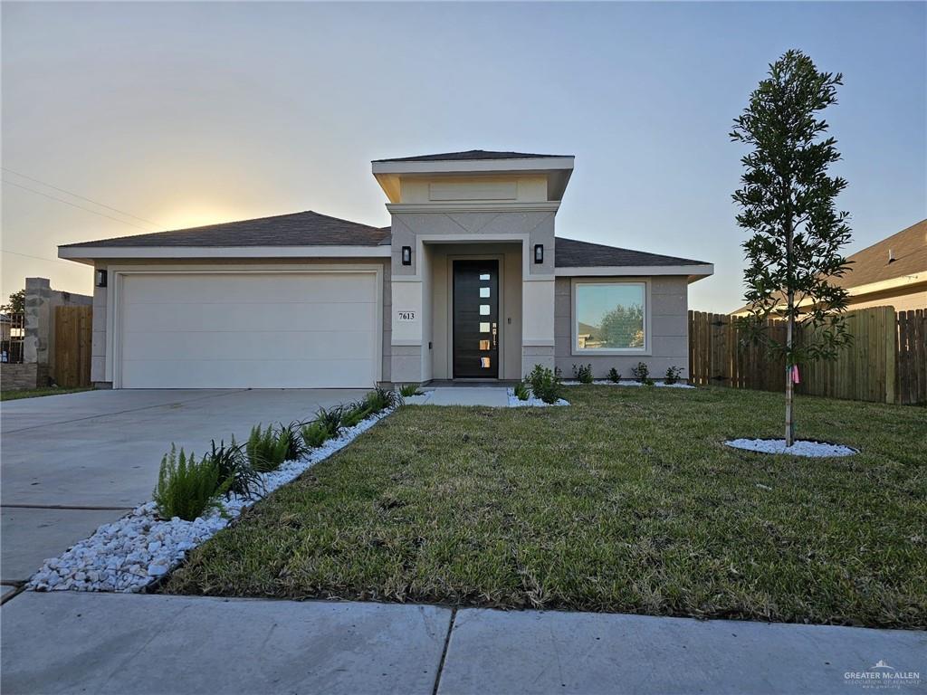 View of front facade featuring a garage and a lawn