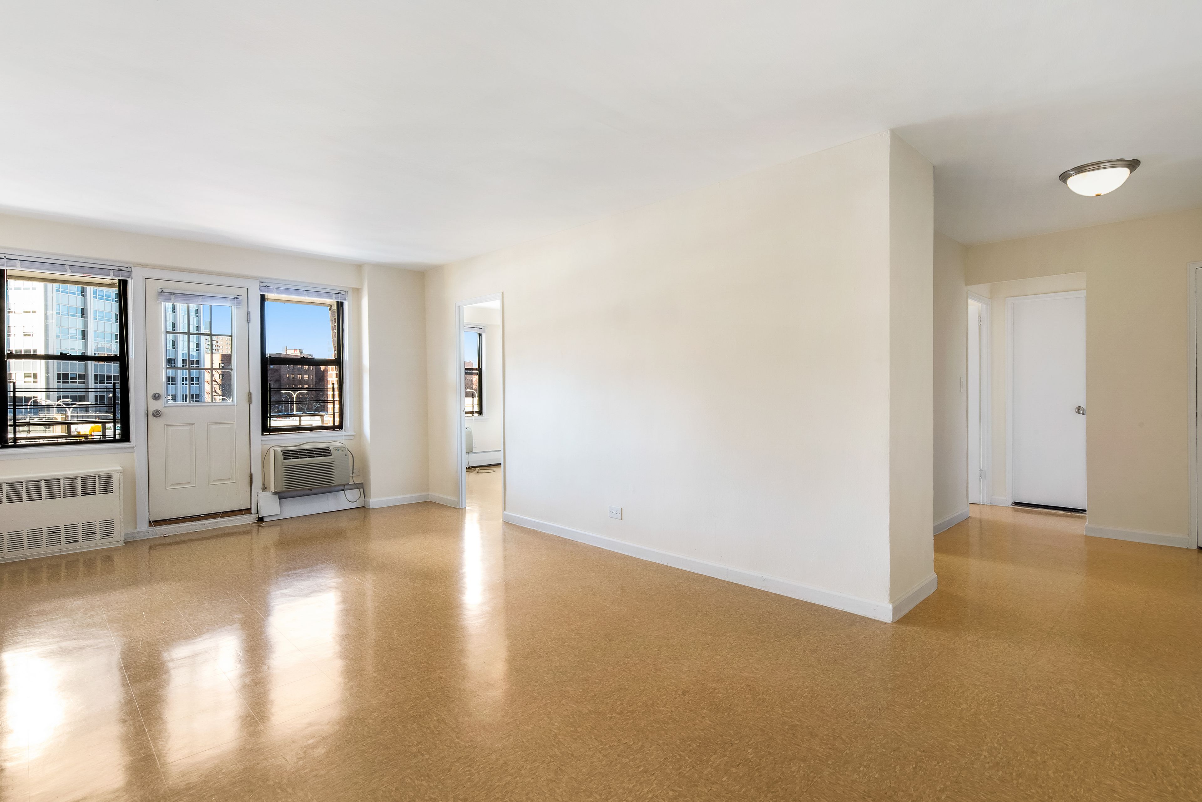 an empty room with a kitchen and window