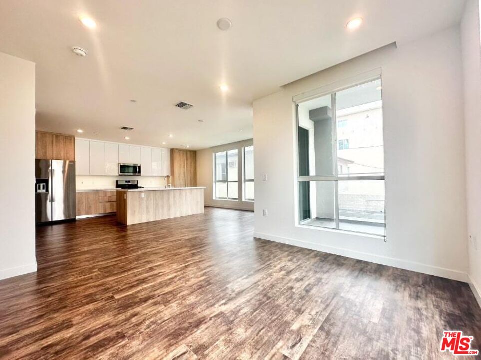 a view of a kitchen with a sink and dishwasher a refrigerator with wooden floor