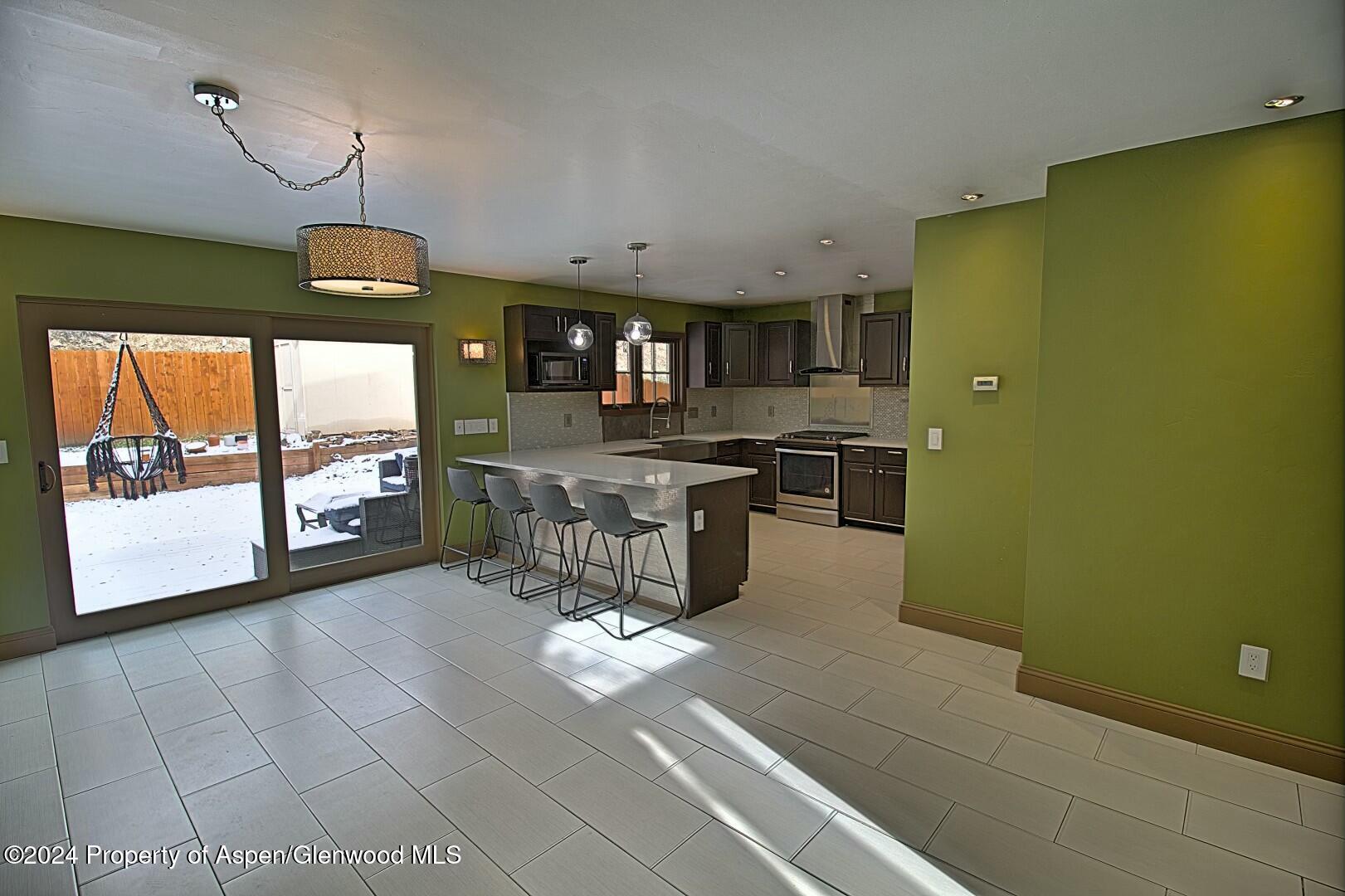 a room with stainless steel appliances kitchen island granite countertop furniture a rug and a window