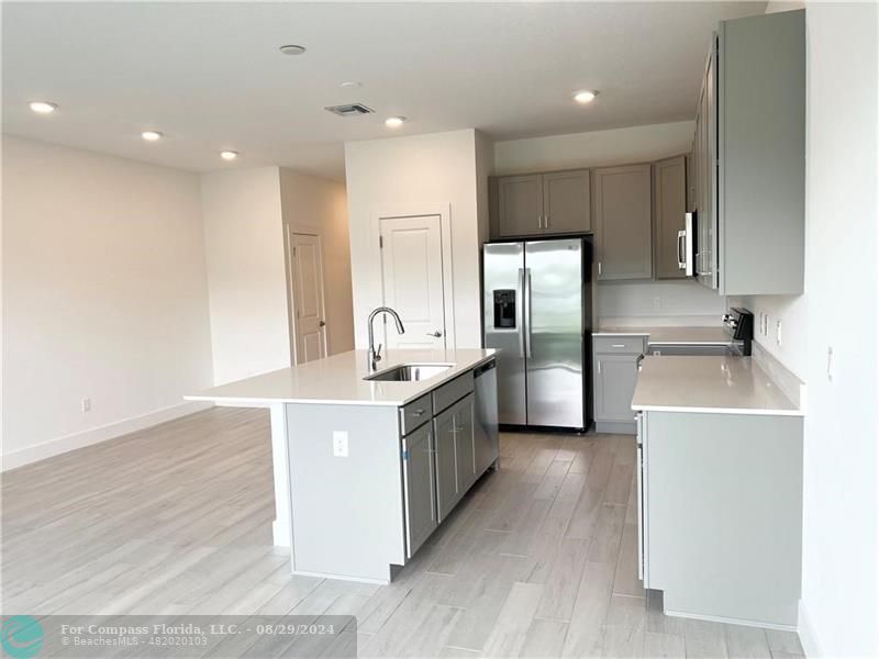 a kitchen with stainless steel appliances a sink a stove a refrigerator and cabinets