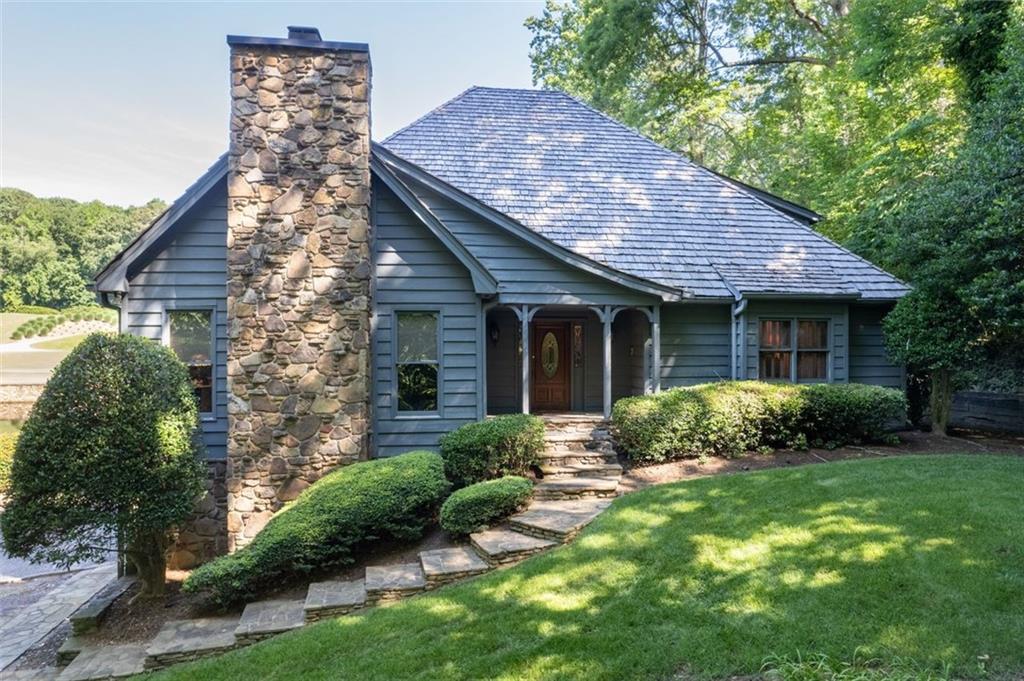 a view of a house with a yard plants and large tree