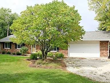 a front view of a house with a garden and trees