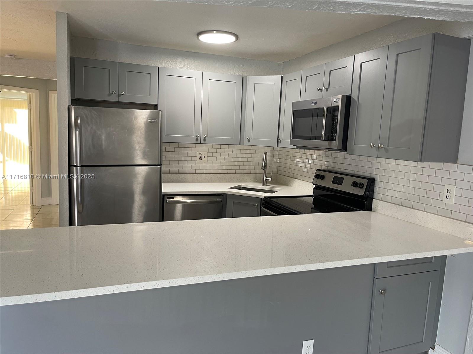 a kitchen with stainless steel appliances a refrigerator sink and microwave