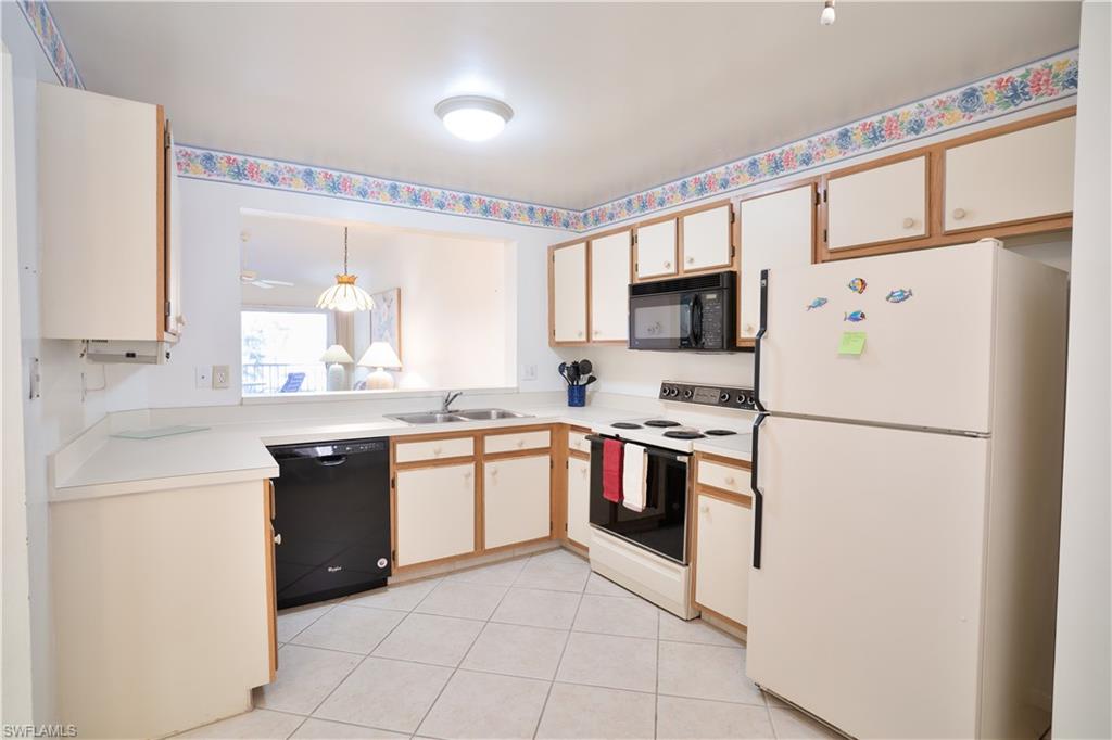 a white kitchen with granite countertop a refrigerator stove top oven and sink