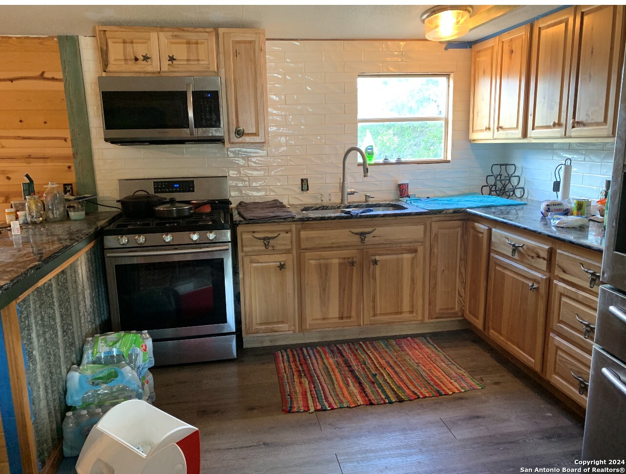 a kitchen with stainless steel appliances a stove a sink cabinets and a window