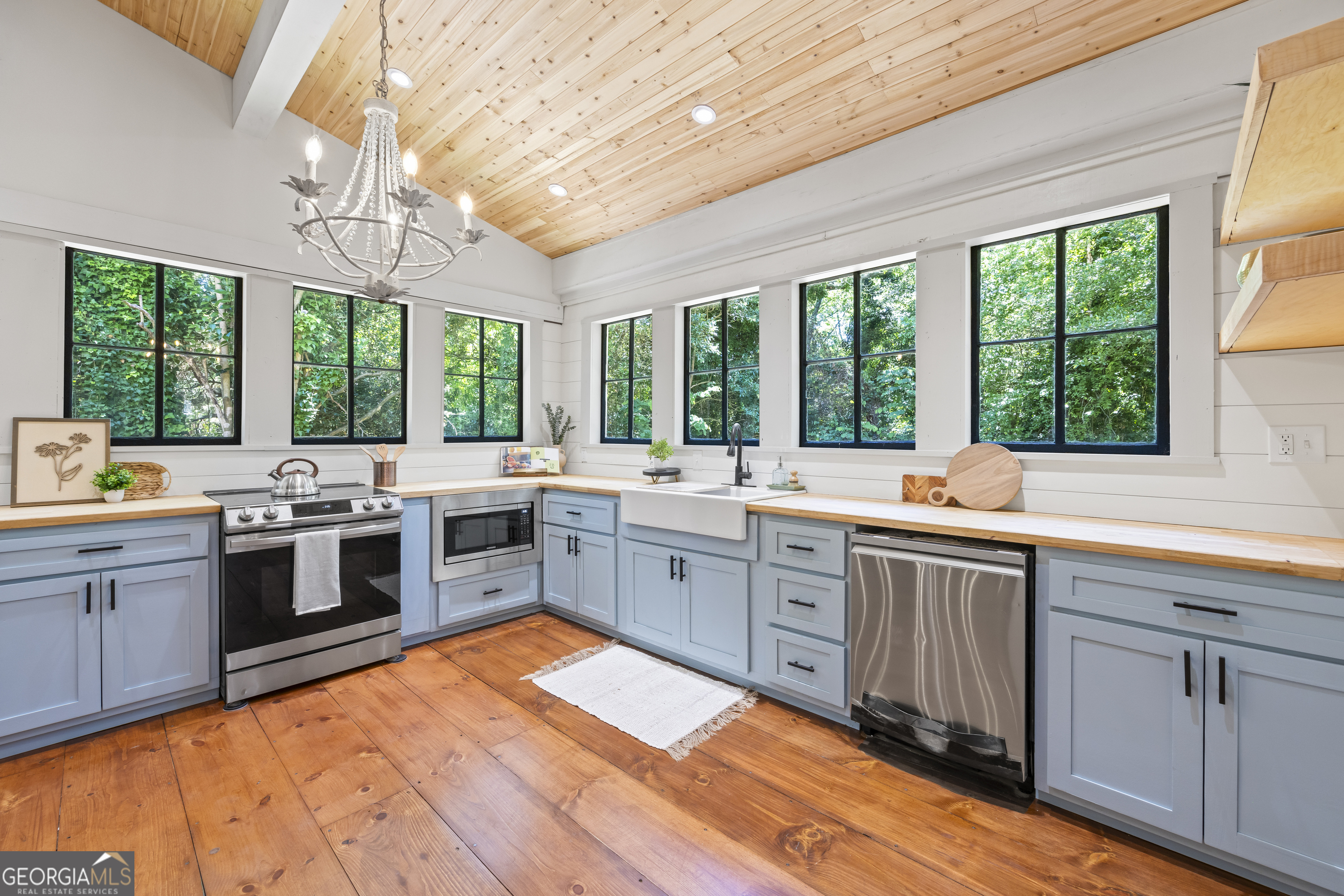 a open kitchen with stainless steel appliances granite countertop a white stove top oven sink and cabinets next to a large window