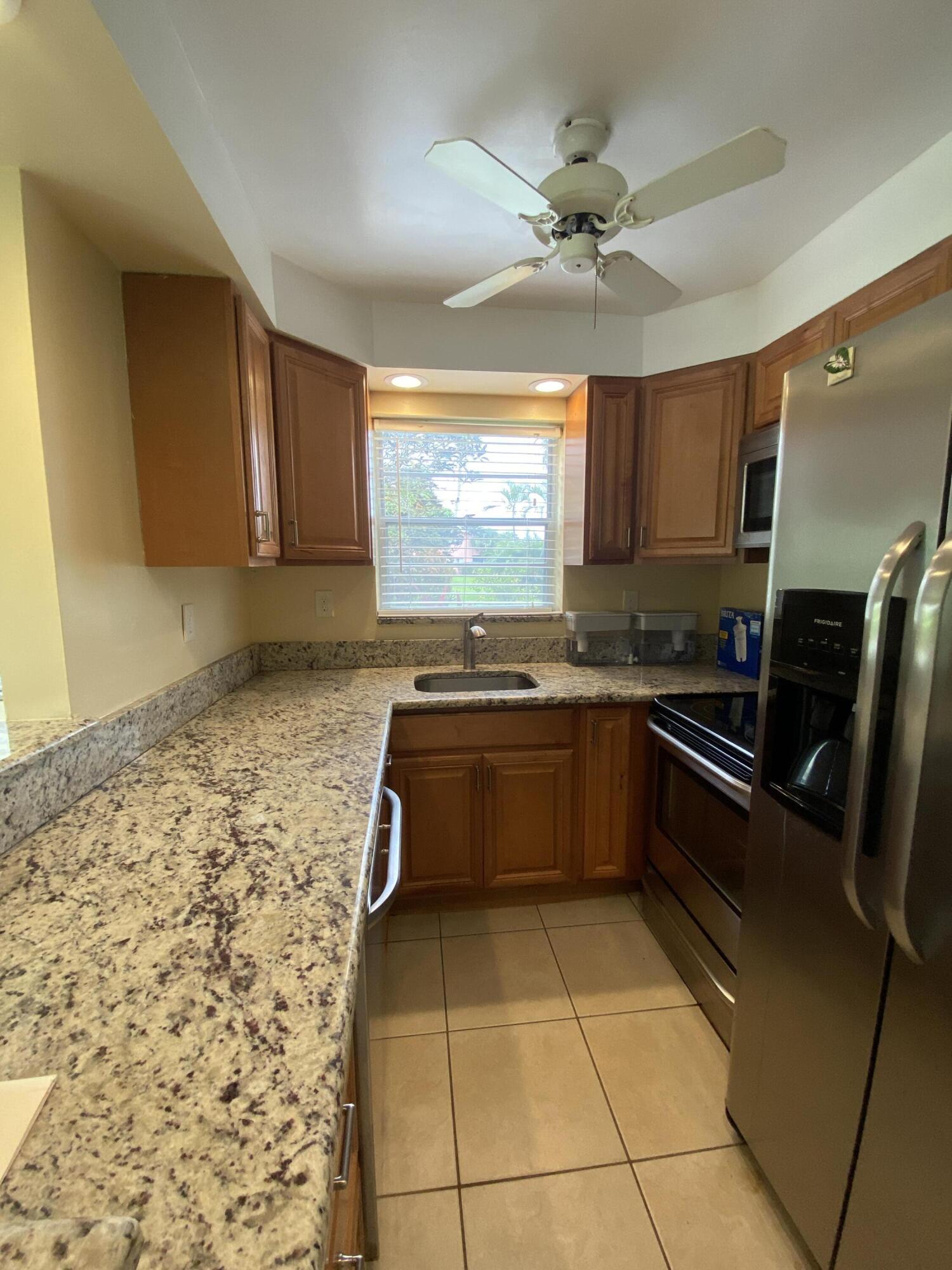 a kitchen with granite countertop a sink a counter top space cabinets and stainless steel appliances