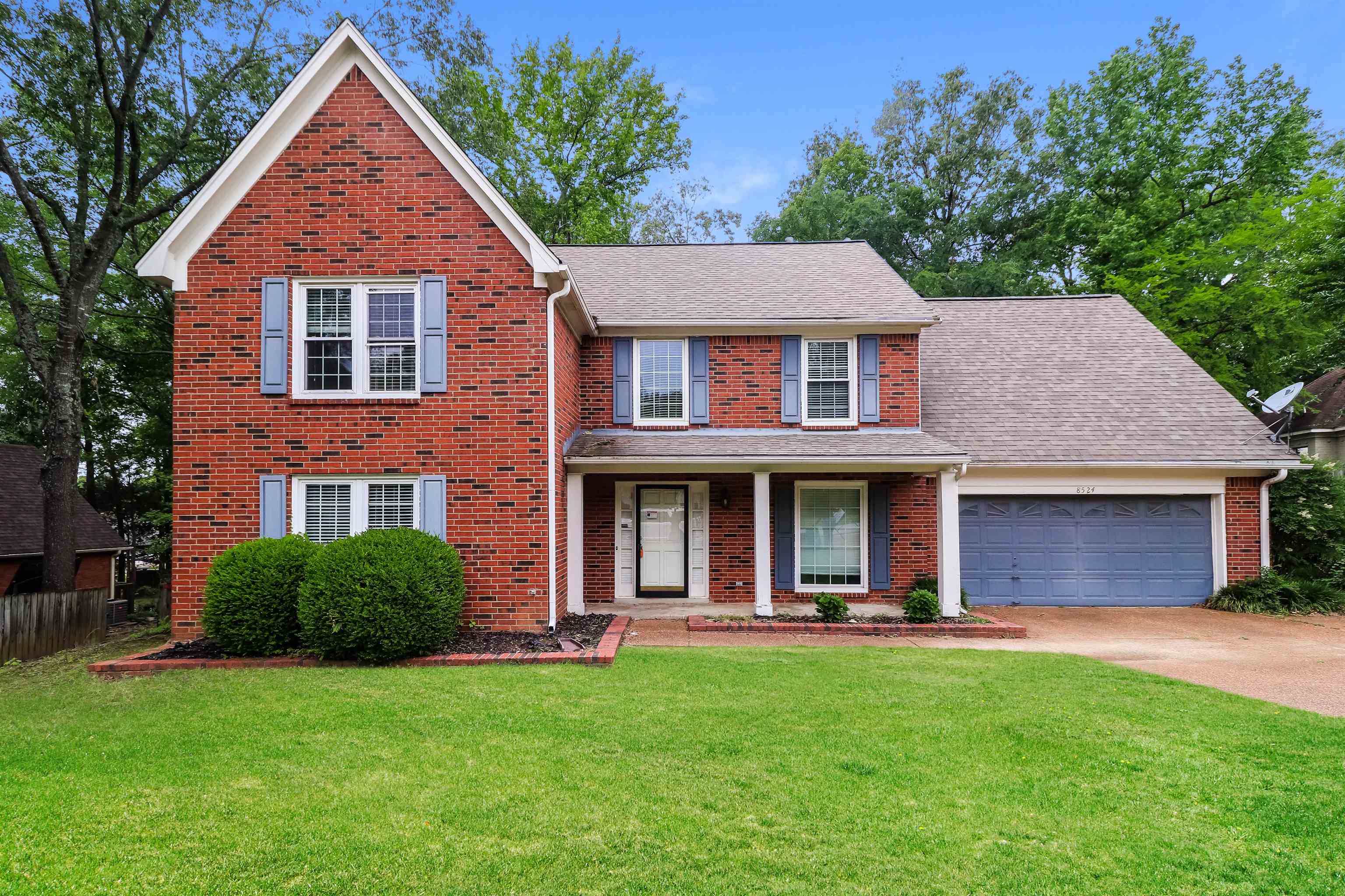 View of front facade featuring a garage and a front lawn