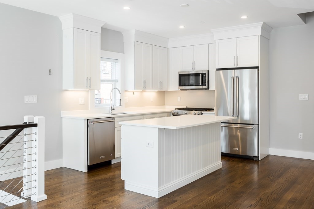 a kitchen with kitchen island granite countertop a refrigerator and a stove top oven