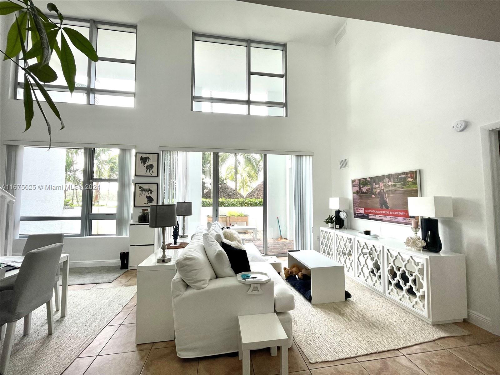 a living room with furniture large windows and wooden floor