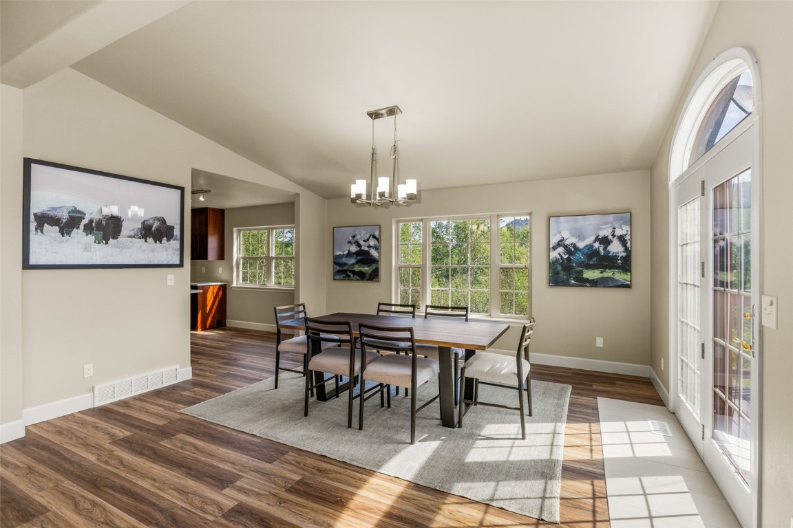 a dining room with wooden floor a chandelier a wooden table and chairs