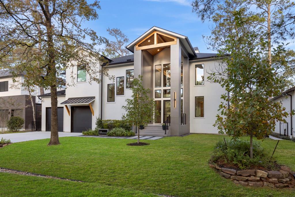 Contemporary two-story home with a sleek facade, large windows, and a welcoming entryway. It features a spacious front yard with mature trees and a double garage with parking for four vehicles. Ideal for contemporary living in a serene golf course neighborhood.