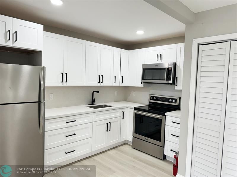 a kitchen with stainless steel appliances a refrigerator stove and white cabinets