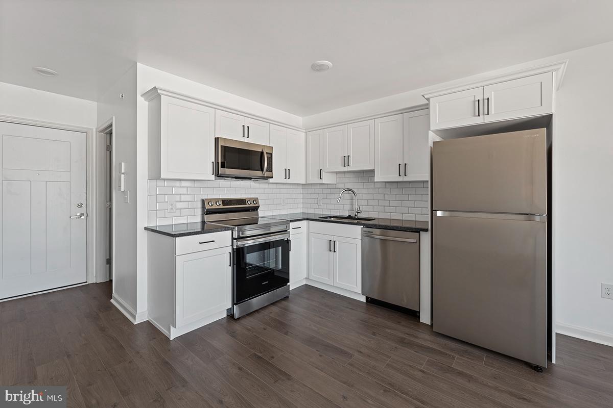 a kitchen with a refrigerator stove and wooden floor