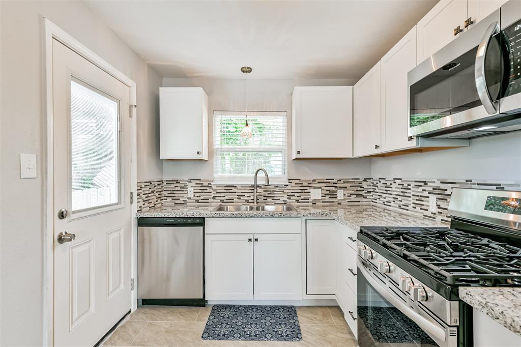 a kitchen with granite countertop a stove a sink and a microwave