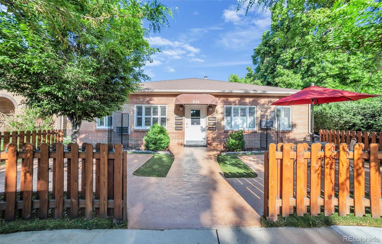 a view of a house with wooden fence next to a yard