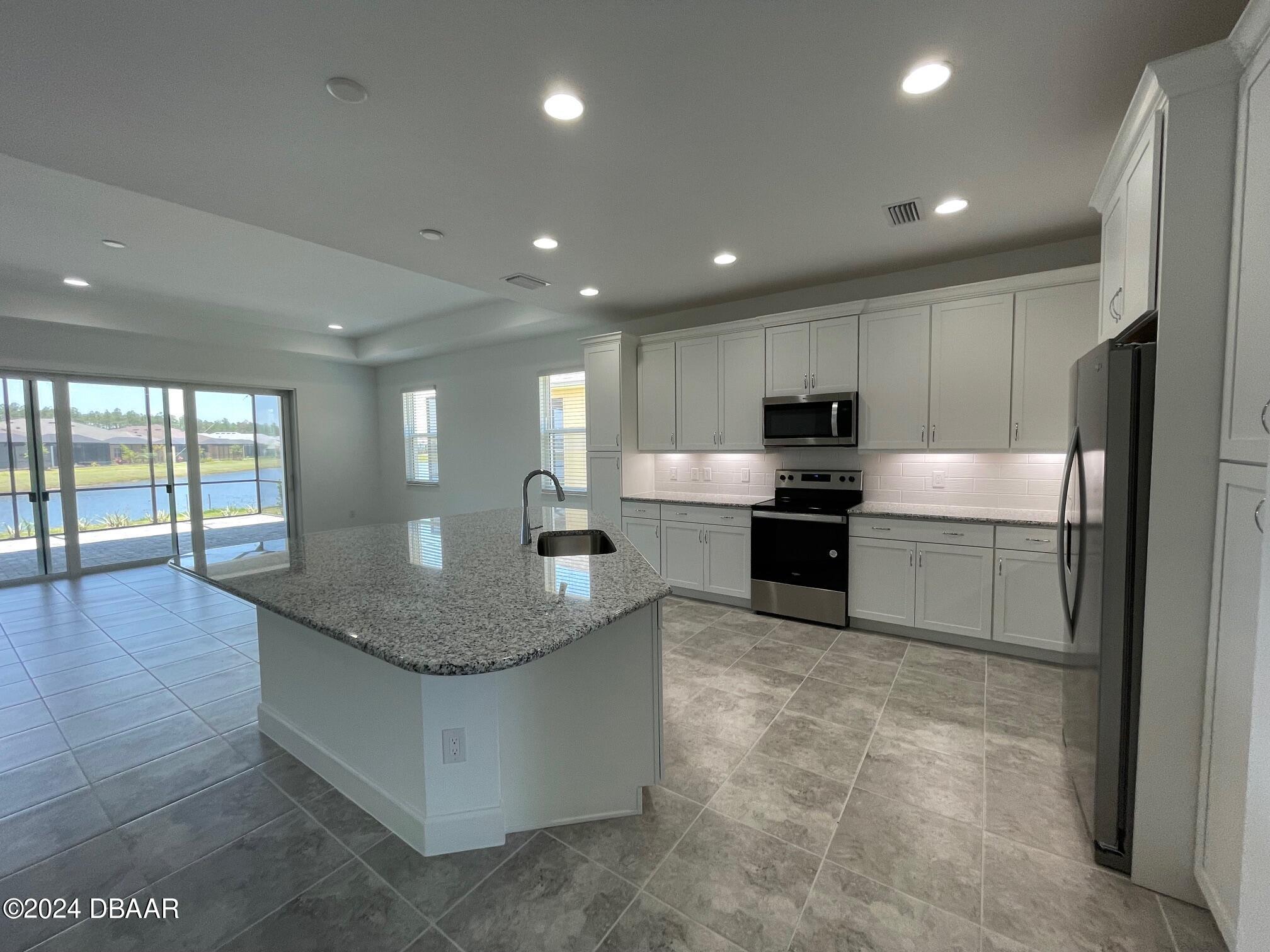 a kitchen with stainless steel appliances granite countertop a sink a stove and a refrigerator