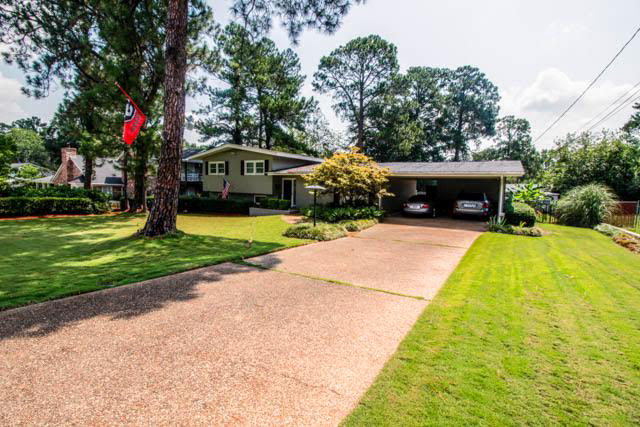 a front view of a house with garden and trees