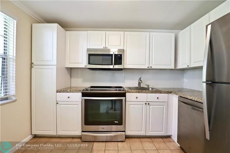 a kitchen with stainless steel appliances granite countertop a stove a microwave and a white cabinets