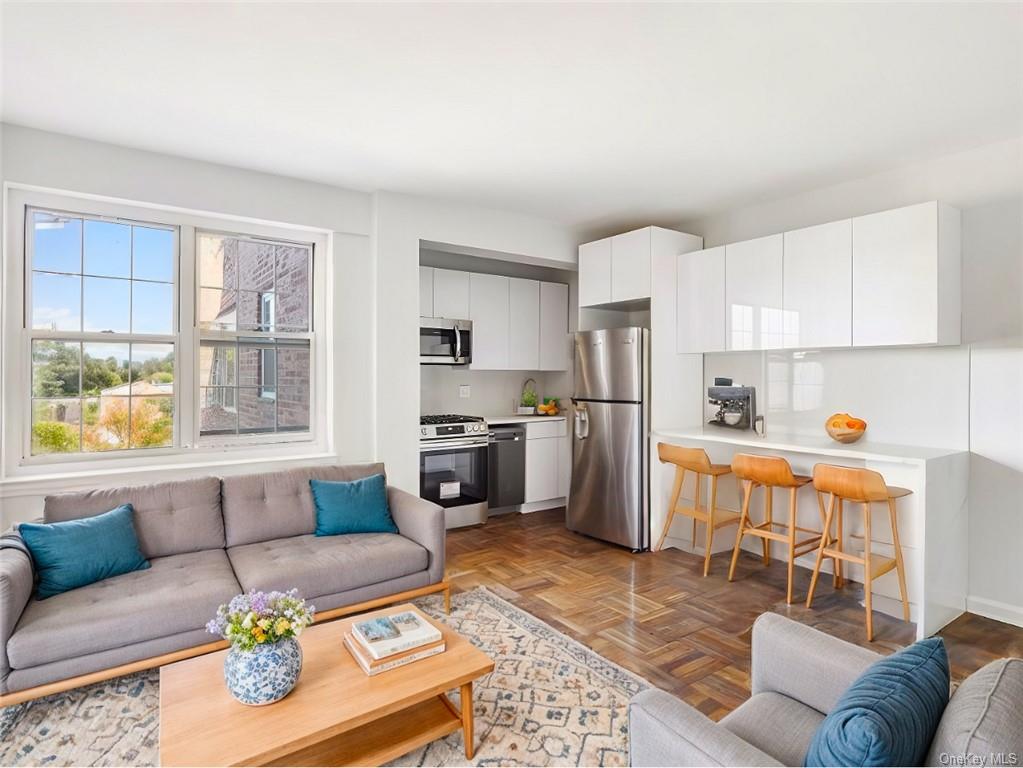 a living room with furniture and a kitchen area with a stove top oven