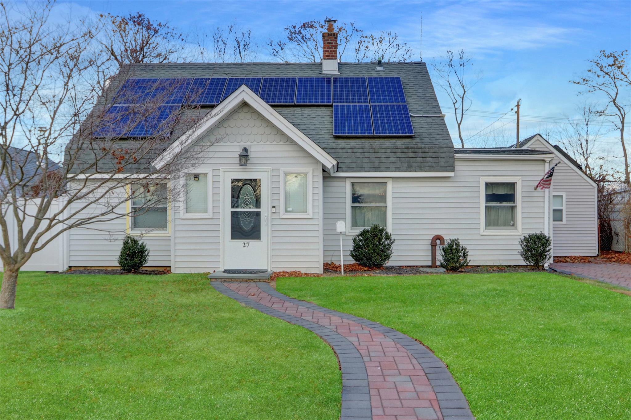 View of front of house with solar panels and a front lawn