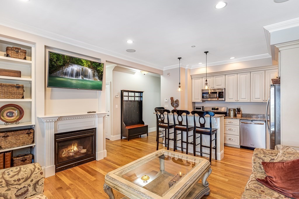 a living room with stainless steel appliances furniture a fireplace and a flat screen tv