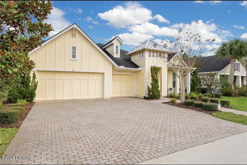 a view of a white house next to a yard and a tree