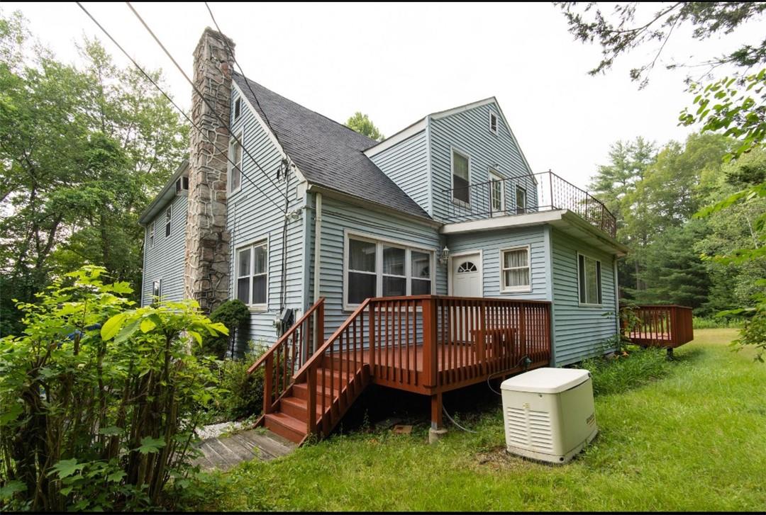 Back of property featuring a deck and a lawn