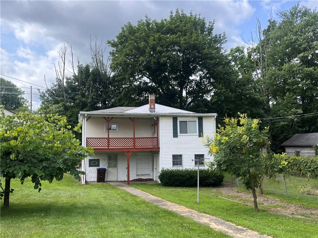 a view of a house with a yard and a large tree