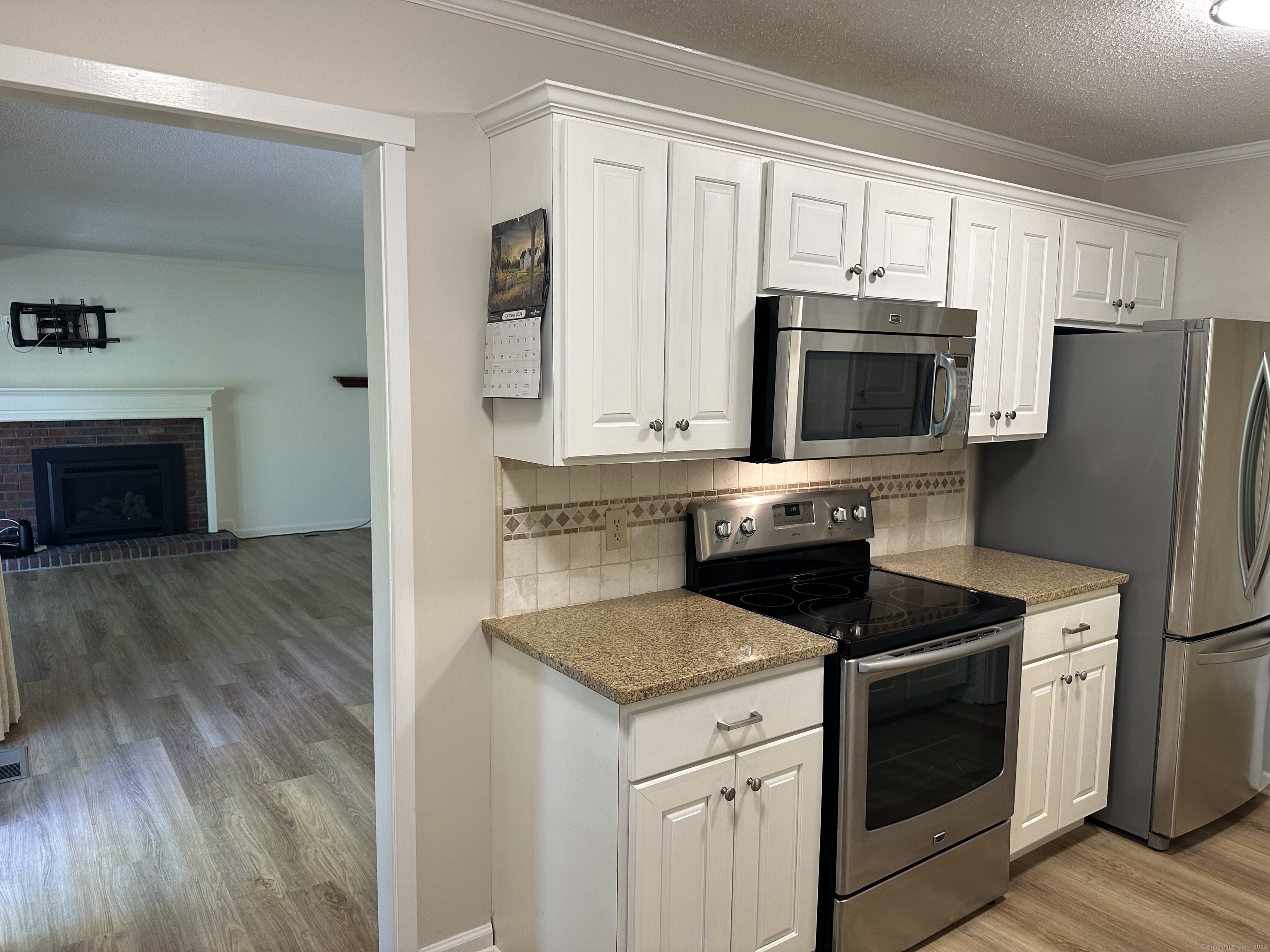 a kitchen with granite countertop a refrigerator stove and microwave