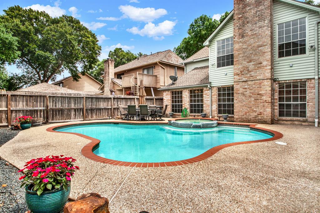 A serene backyard oasis featuring a sparkling pool and an inviting hot tub. The pool's crystal-clear water glistens under the sunlight, while the hot tub offers a perfect spot for relaxation.