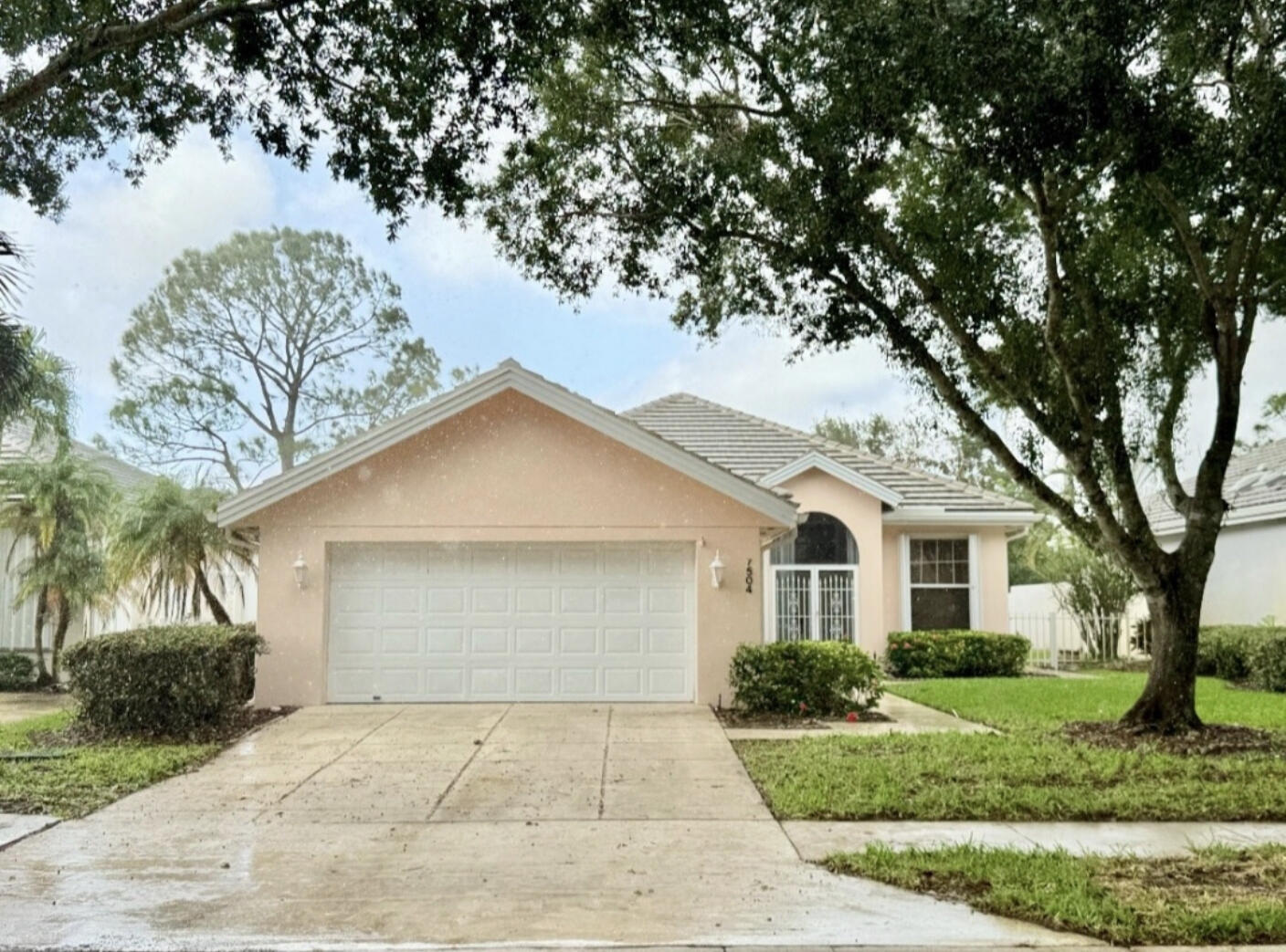 a front view of a house with a garden and trees