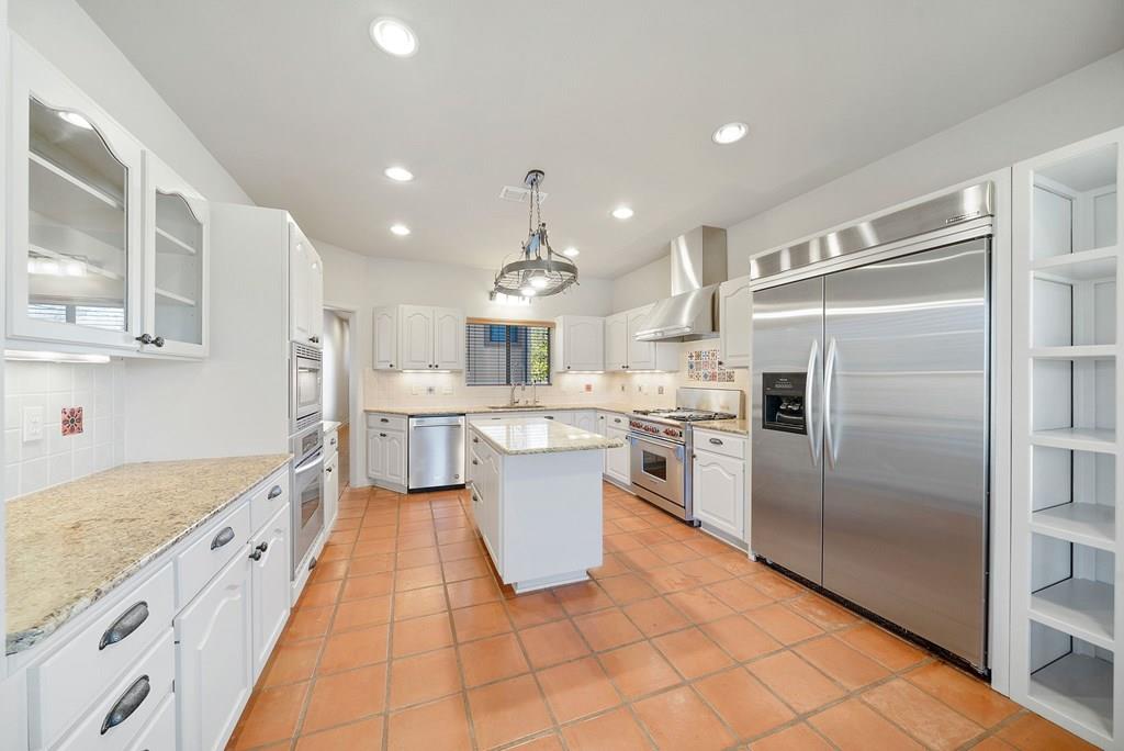 a large kitchen with a large counter top a sink stainless steel appliances and cabinets