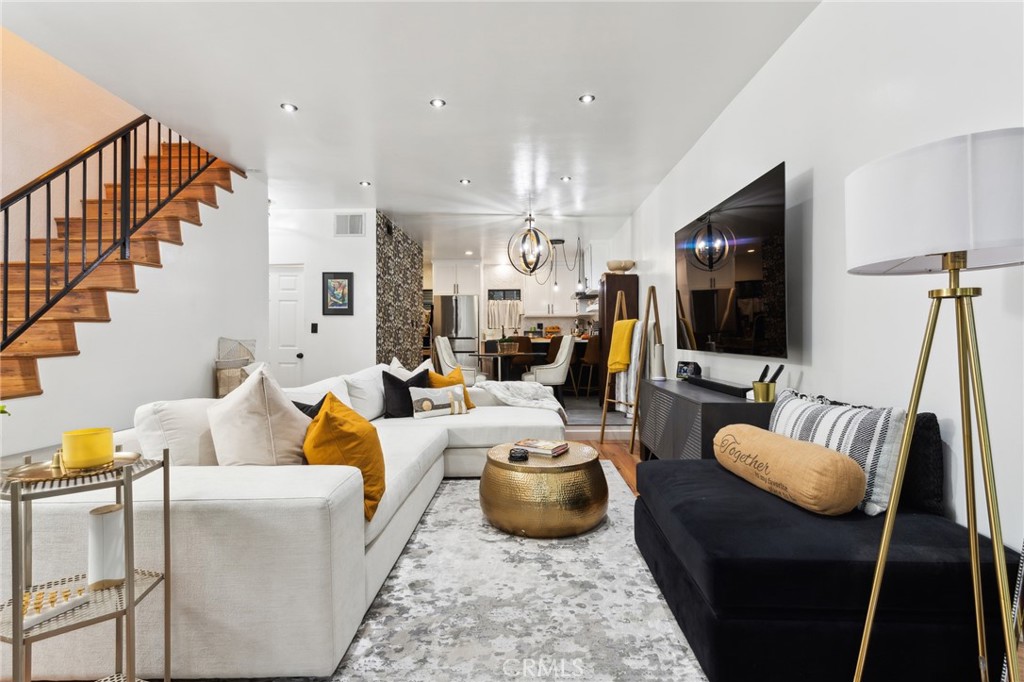 a living room with furniture a flat screen tv and kitchen view