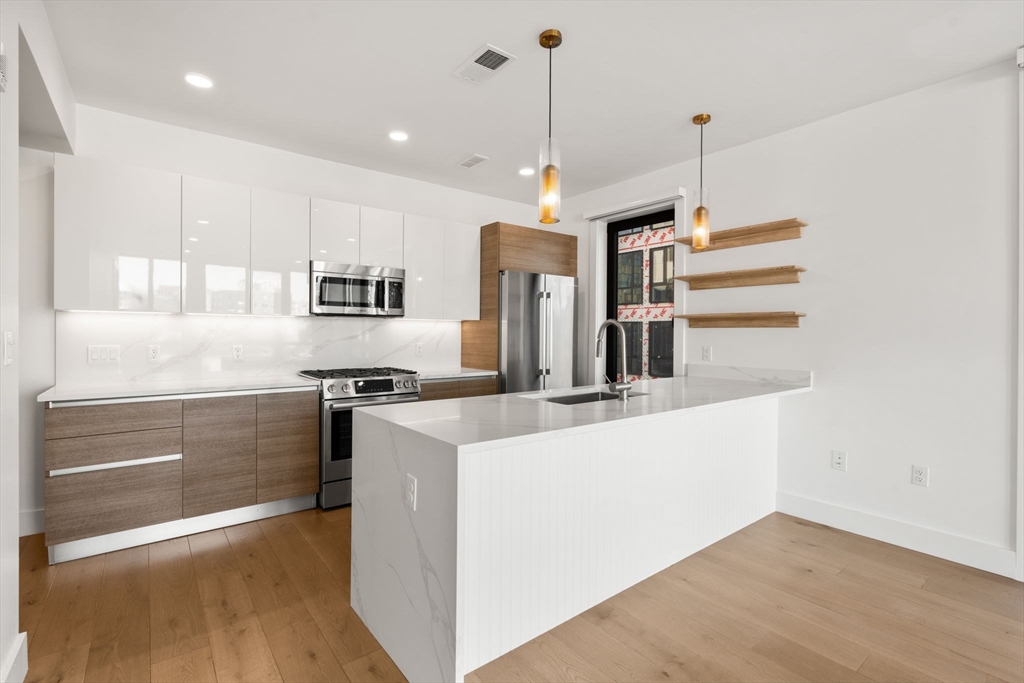 a kitchen with kitchen island a stove a sink a center island and wooden floor