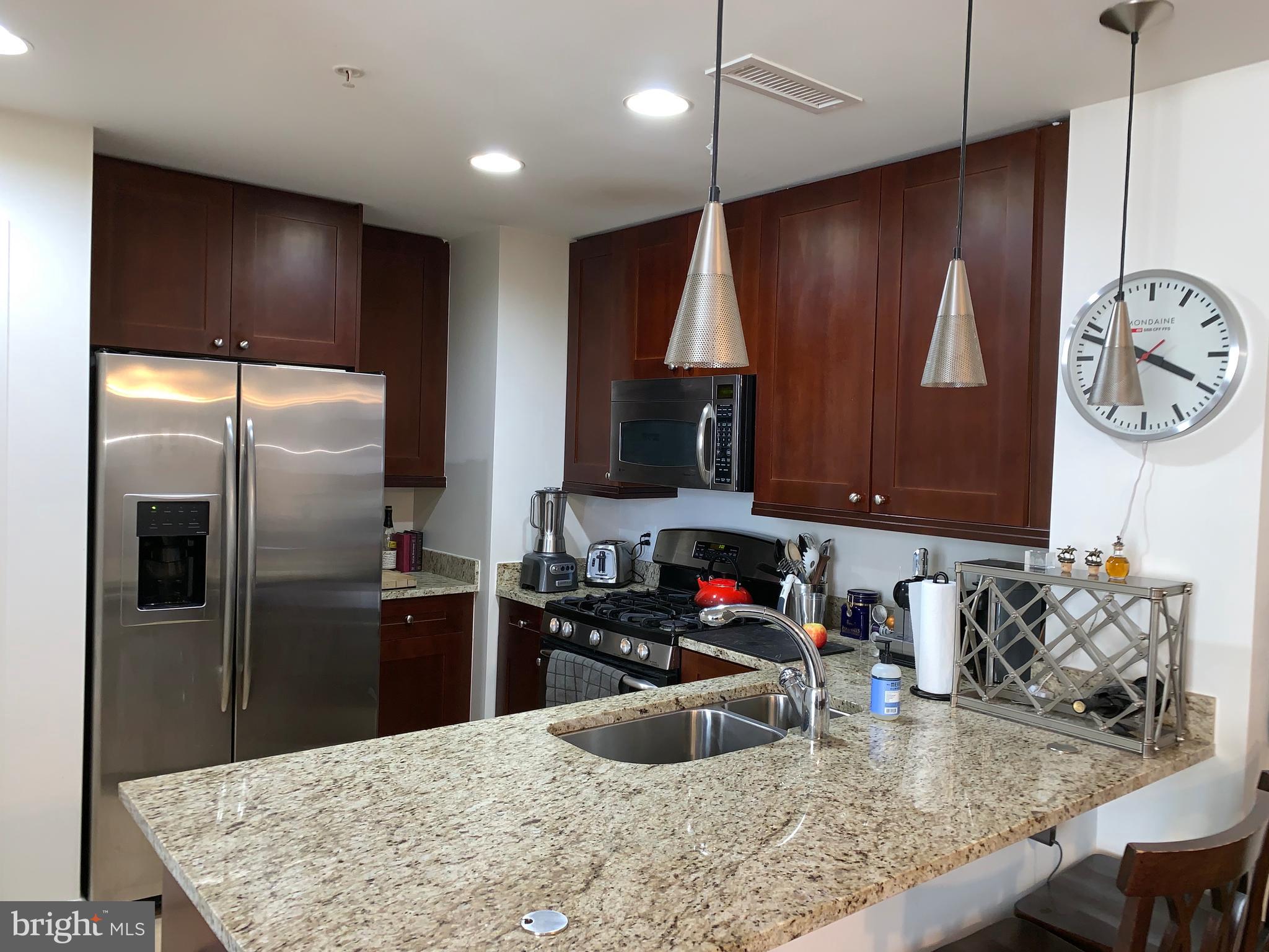 a kitchen with stainless steel appliances granite countertop a sink refrigerator and microwave