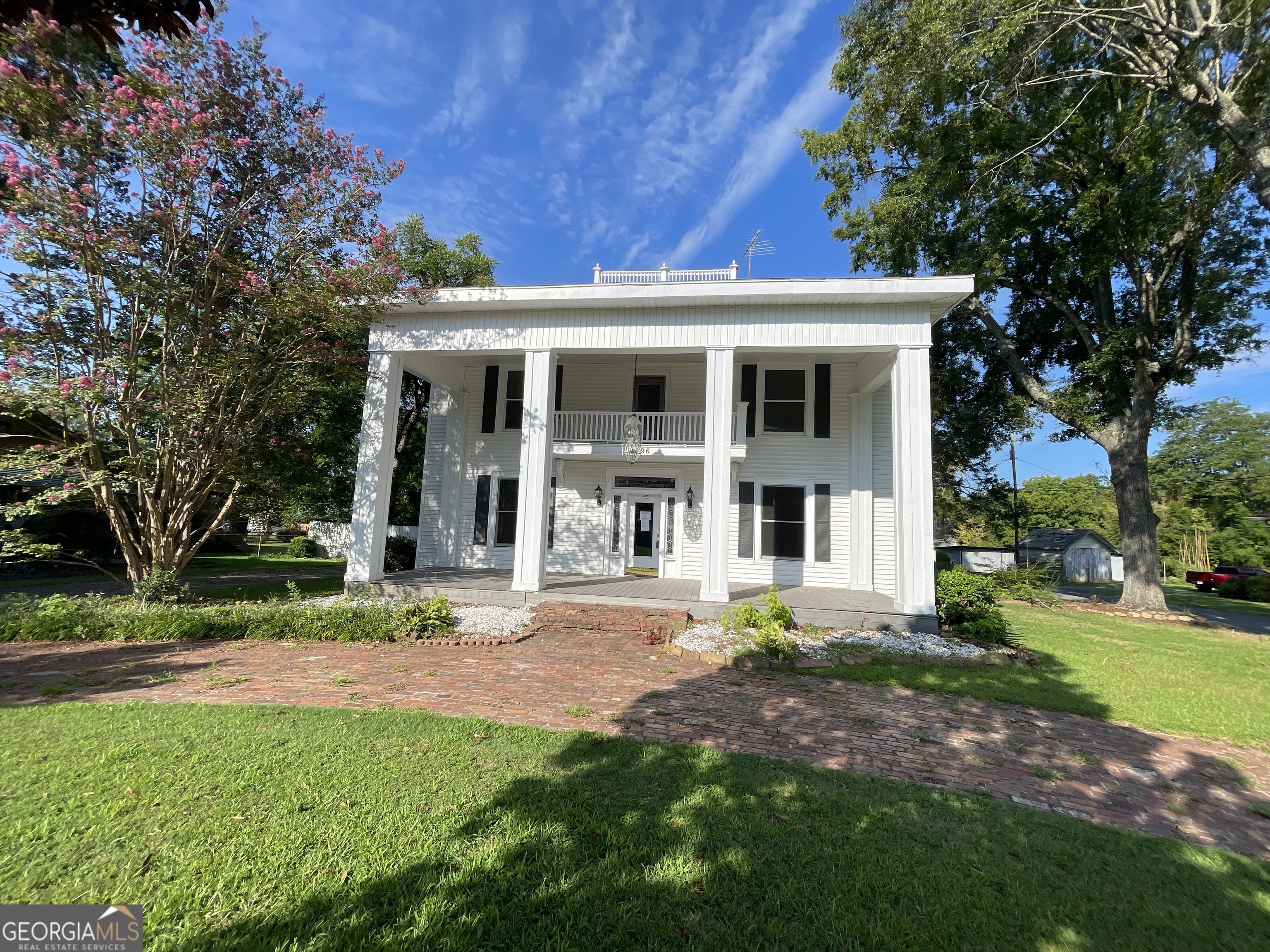 a front view of a house with garden and trees