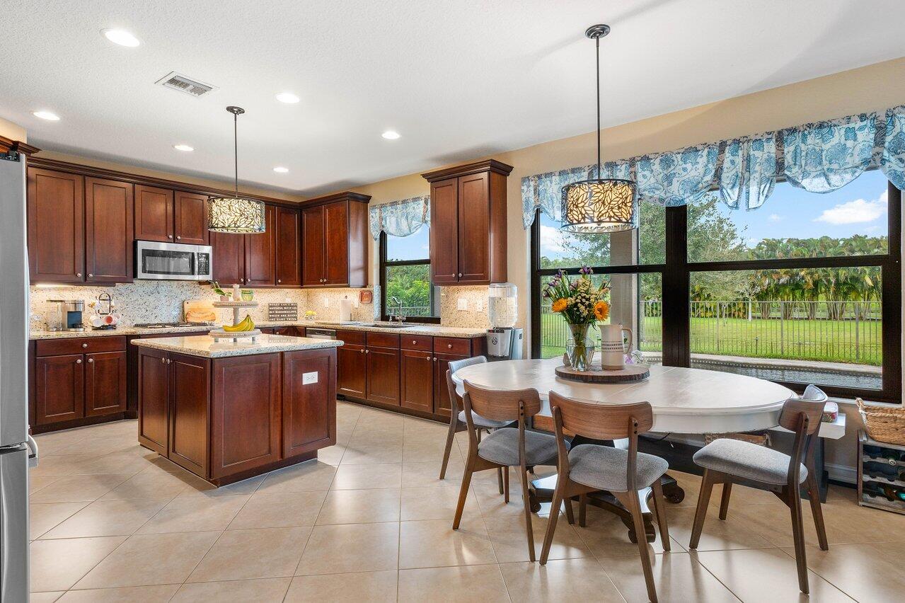 a kitchen with a stove a refrigerator a dining table and chairs with wooden floor