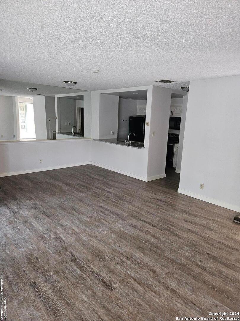 a view of empty room with wooden floor and a window