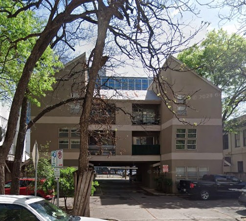 a front view of a building with balcony and trees