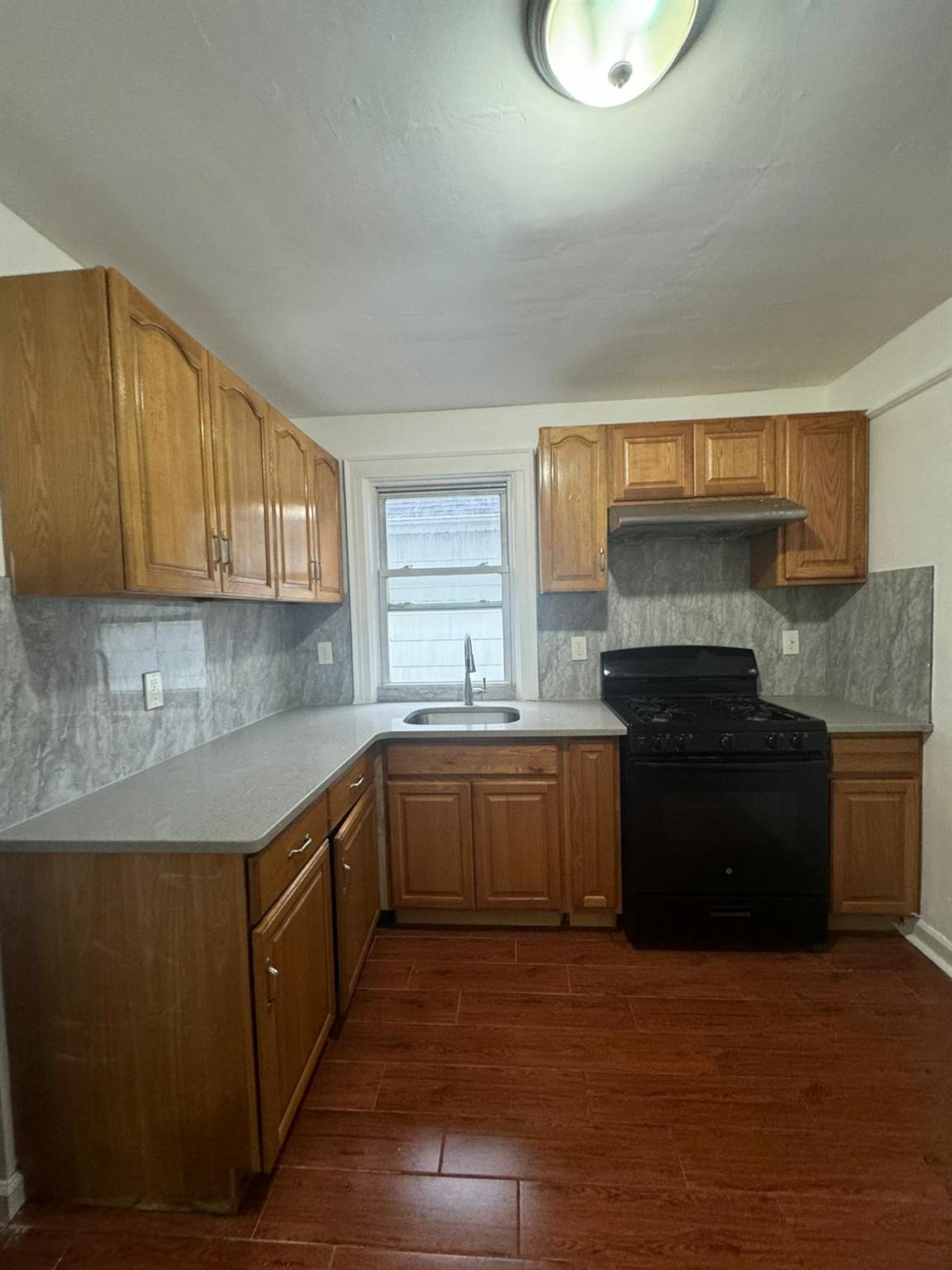 Kitchen with backsplash, gas stove, sink, and dark wood-type flooring